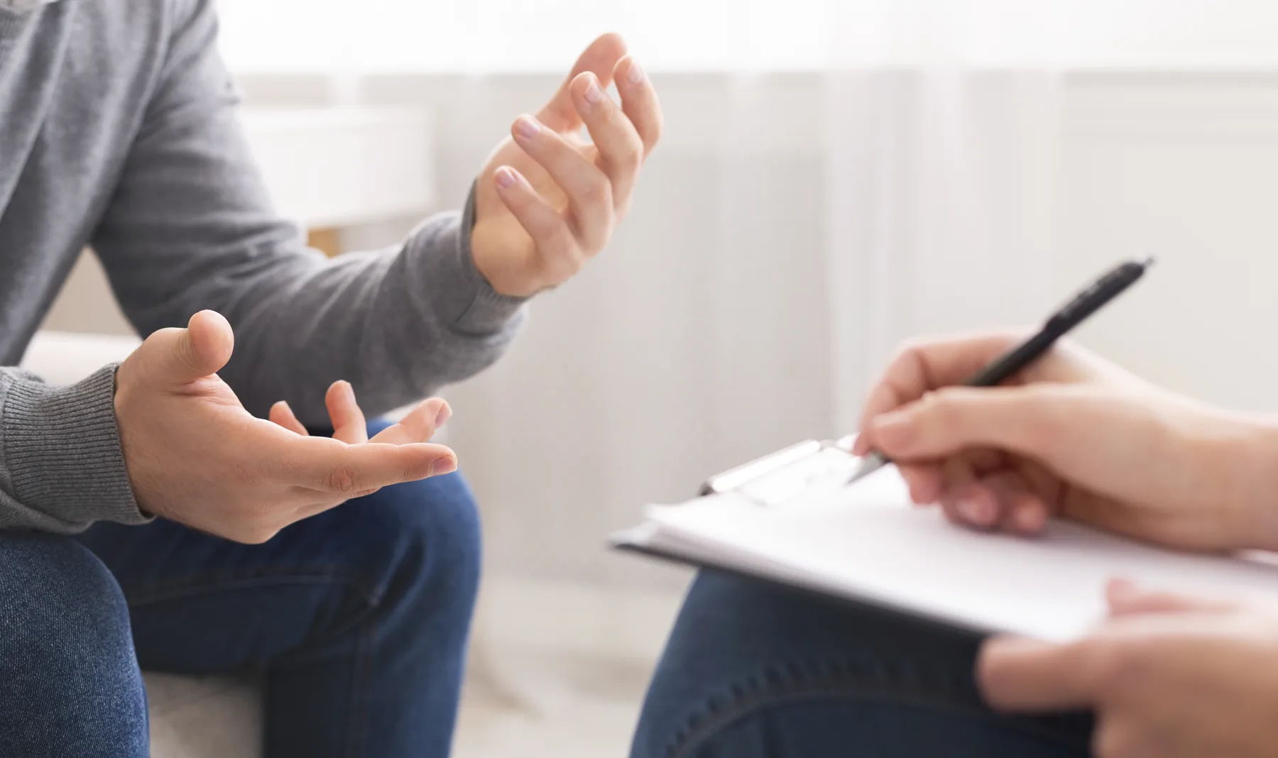 Counselling conversation, hands and notepad