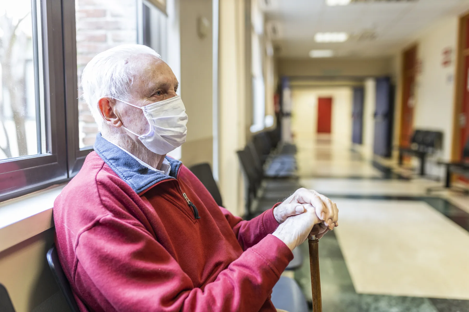 Older man sitting alone in a corridor